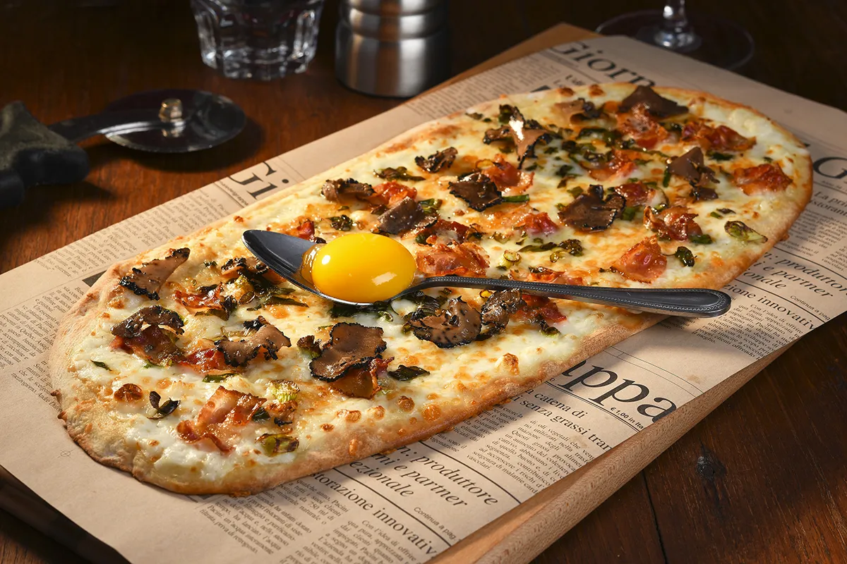 Pizza carbonara sur pâte artisanale avec bacon croustillant et sauce crémeuse