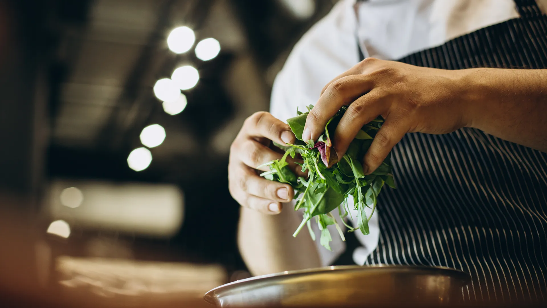 Chef PACINI qui prépare une salade fraîche en cuisine, ingrédients de qualité