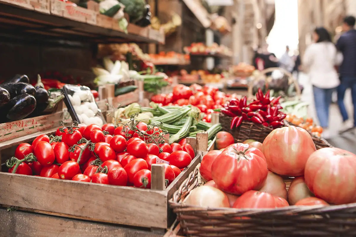 Étal de marché italien avec tomates en grappe, poivrons, aubergines et légumes frais