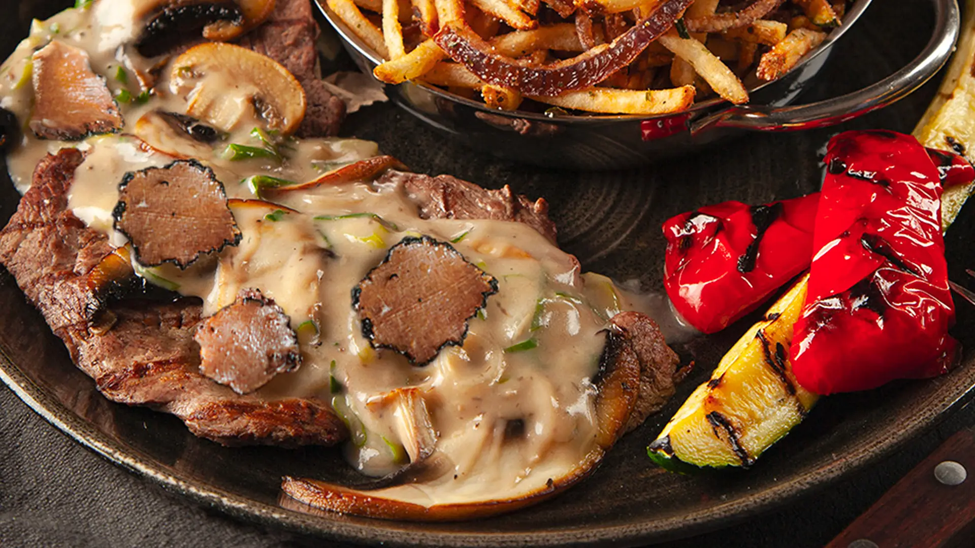 Tranches de veau grillé PACINI nappées de copeaux de truffe noire, sauce crémeuse aux champignons et frites maison
